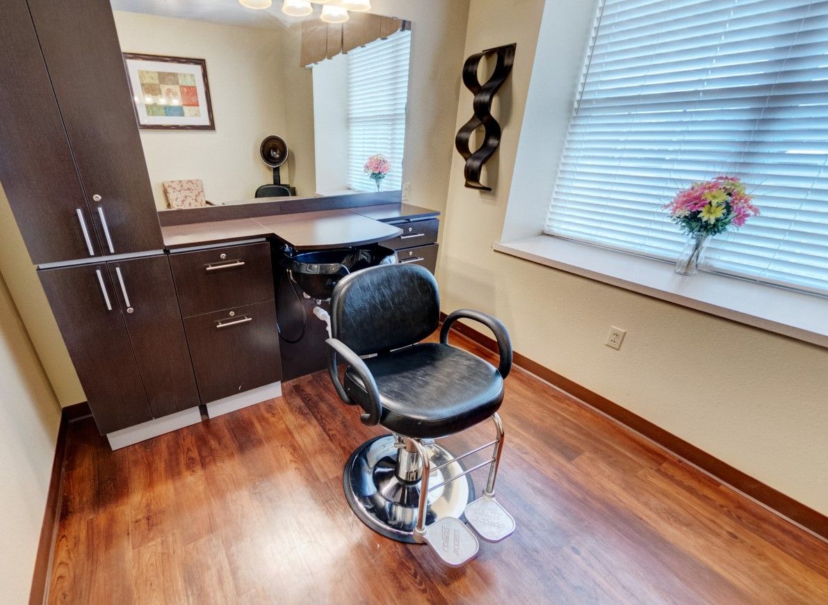 A cozy hair salon setup featuring a styling chair, mirror, and wooden flooring.