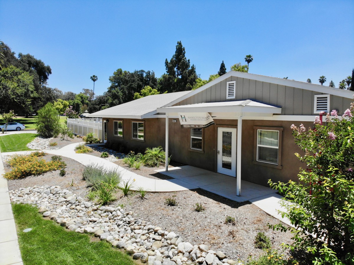 A single-story house with a well-maintained garden and driveway under a clear blue sky.