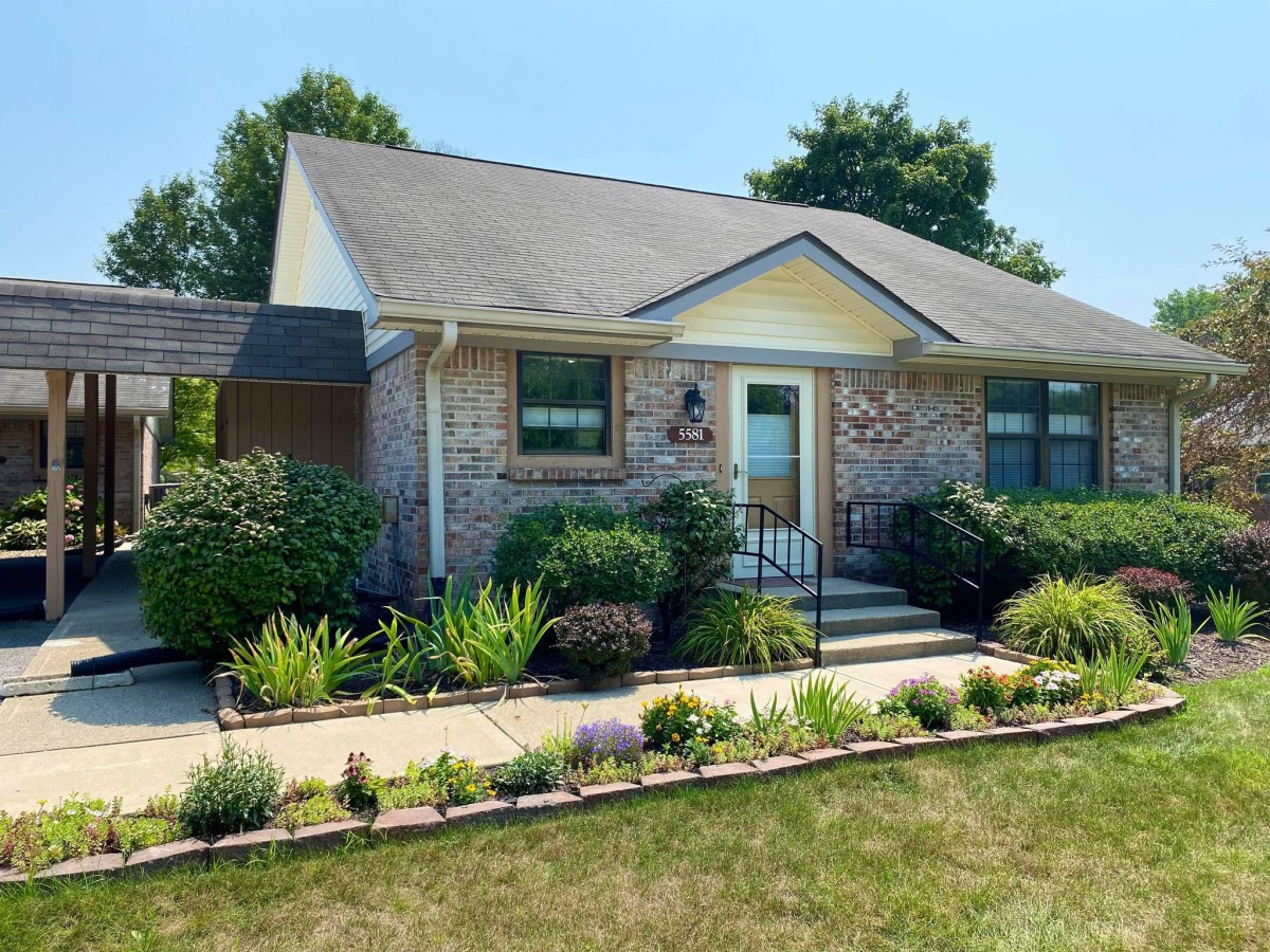 A charming brick house with well-maintained landscaping on a sunny day.