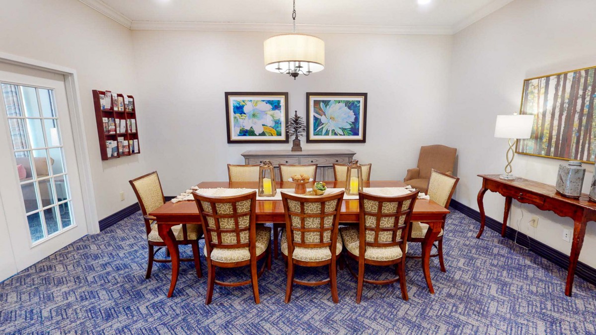 A well-decorated dining room featuring a large wooden table, matching chairs, a chandelier, and framed artwork on the wall.