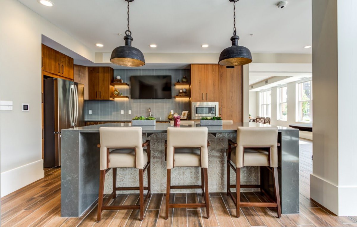 A modern kitchen with a sleek island, featuring bar stools and pendant lighting.
