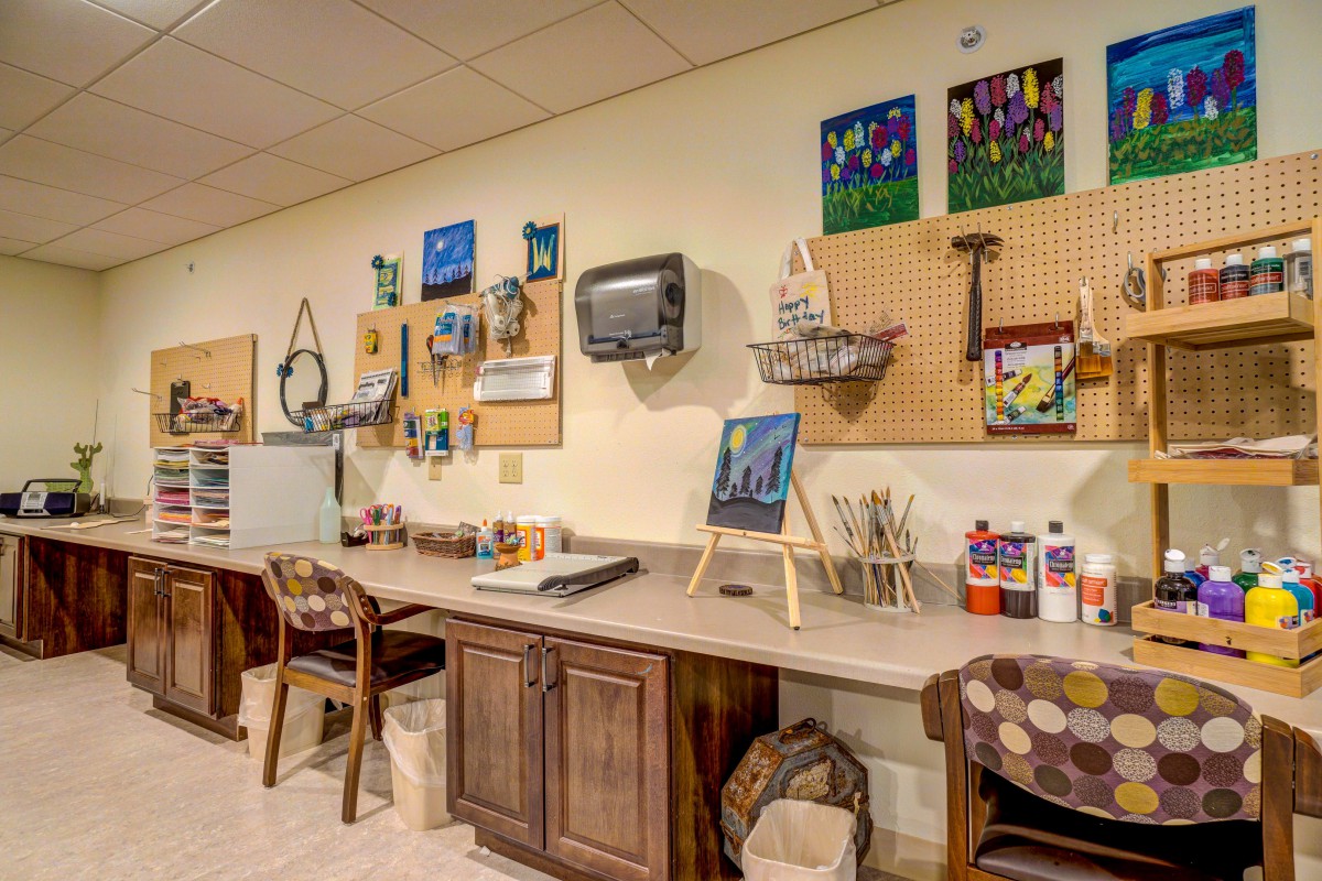 An art studio with a workbench, painting supplies, and tools organized on pegboards.