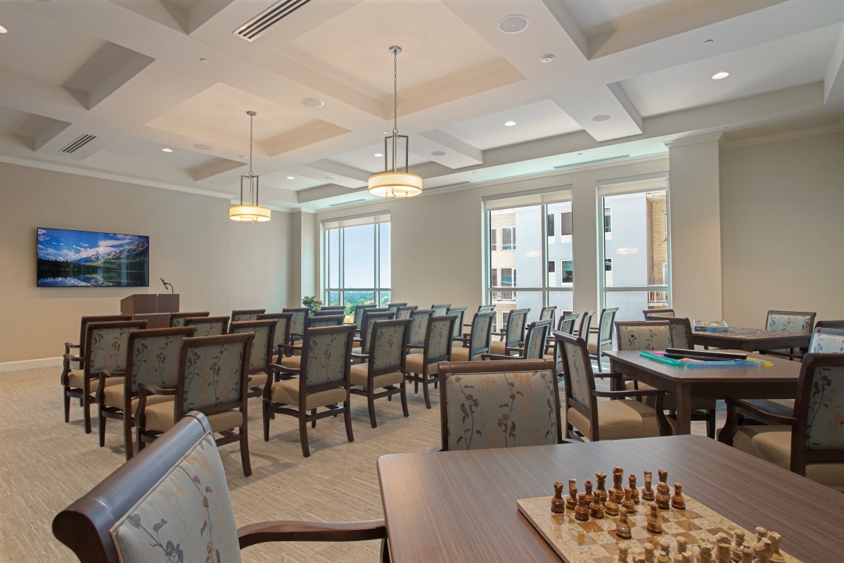 An empty conference room featuring a chess board on the table, with rows of chairs and large windows.