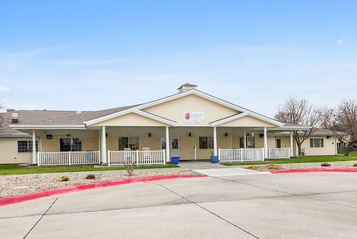 A single-story building with a large porch and driveway area.