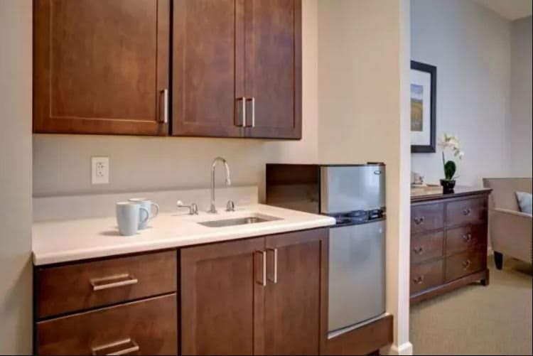 A small kitchenette with wooden cabinets, a sink, and a mini fridge.