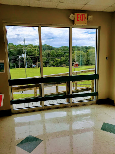 A view through a sliding glass door, showcasing a green landscape under a cloudy sky.
