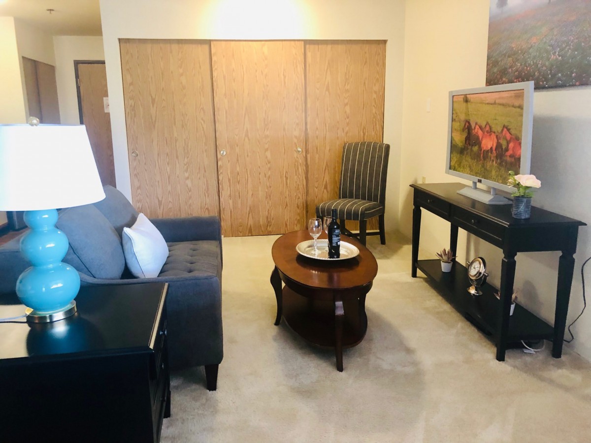A cozy living room with a sofa, coffee table, and TV stand.