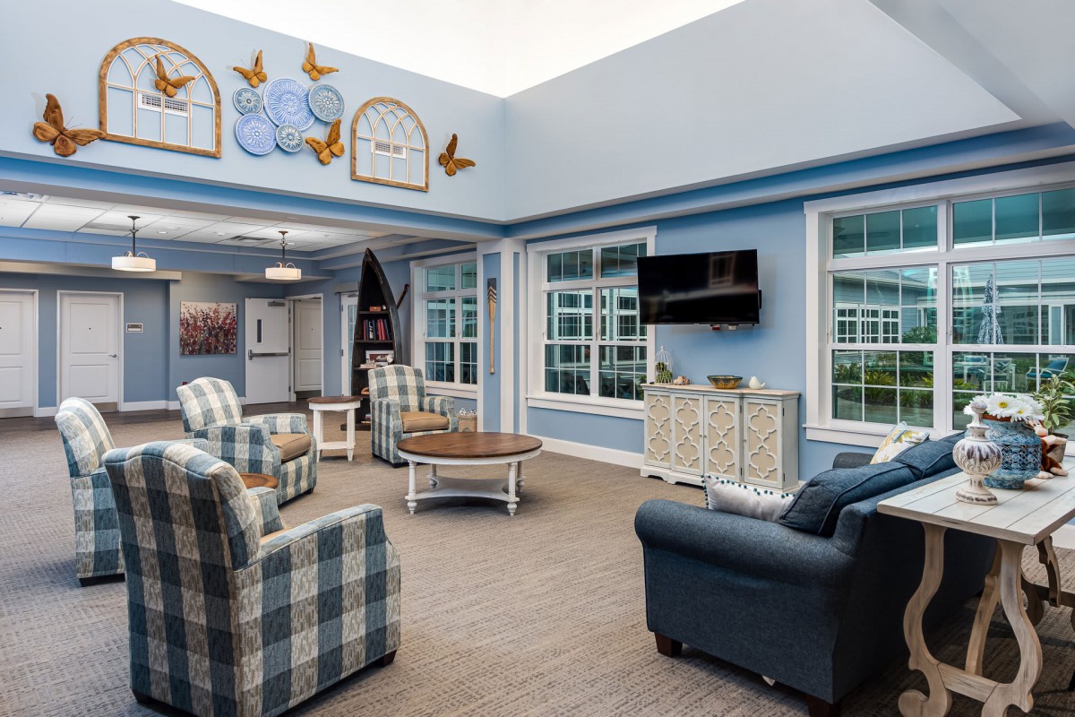 A cozy living room with blue walls, featuring armchairs, a coffee table, and a television.