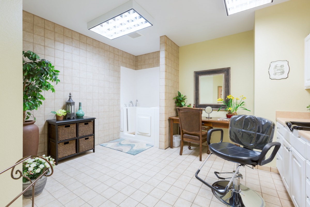 A cozy salon room with a styling chair and a large mirror.