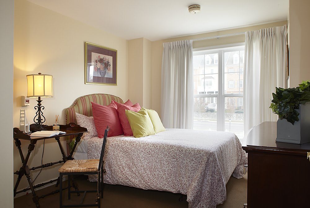 A cozy bedroom with a well-decorated bed and ample natural light.