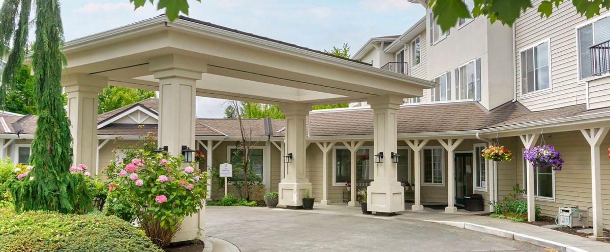 The entrance to a building with columns and a covered driveway.
