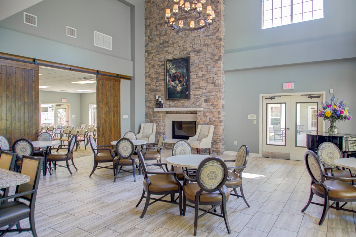 A spacious lounge with elegant seating, a stone fireplace, and a chandelier.