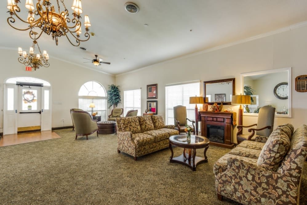 A spacious living room with comfortable seating, a chandelier, and a fireplace.