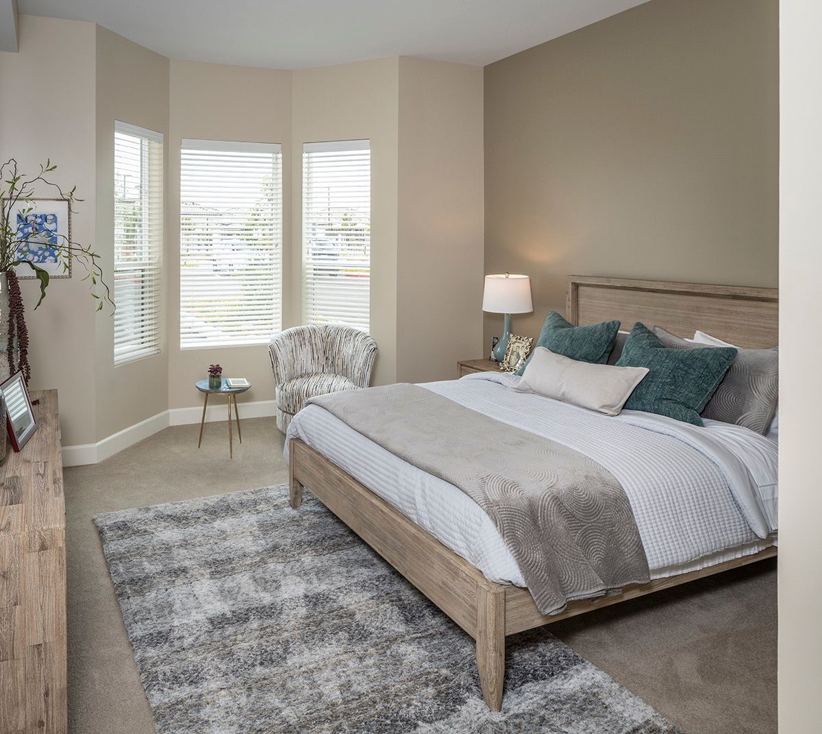 A modern bedroom with a cozy bed, stylish decor, and a large window.