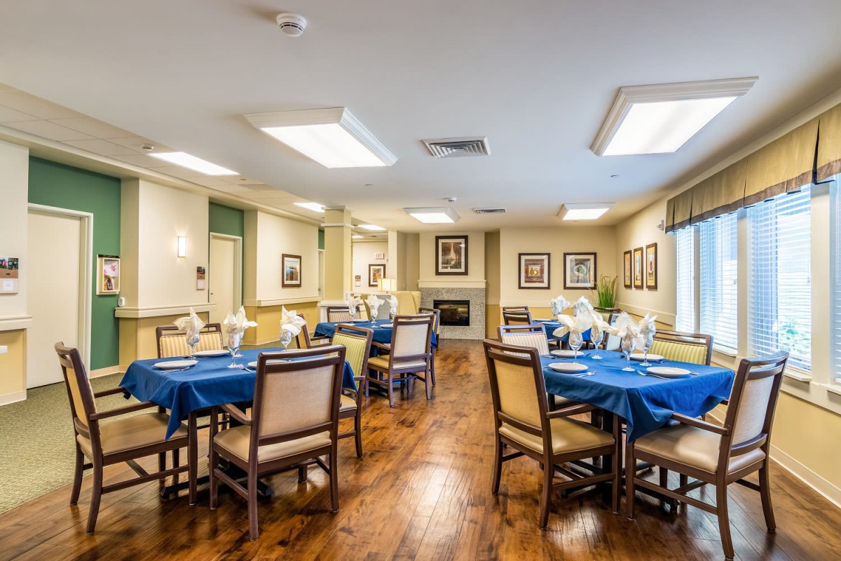 A well-arranged dining room featuring tables set with blue tablecloths and wooden chairs, creating a cozy and inviting atmosphere.