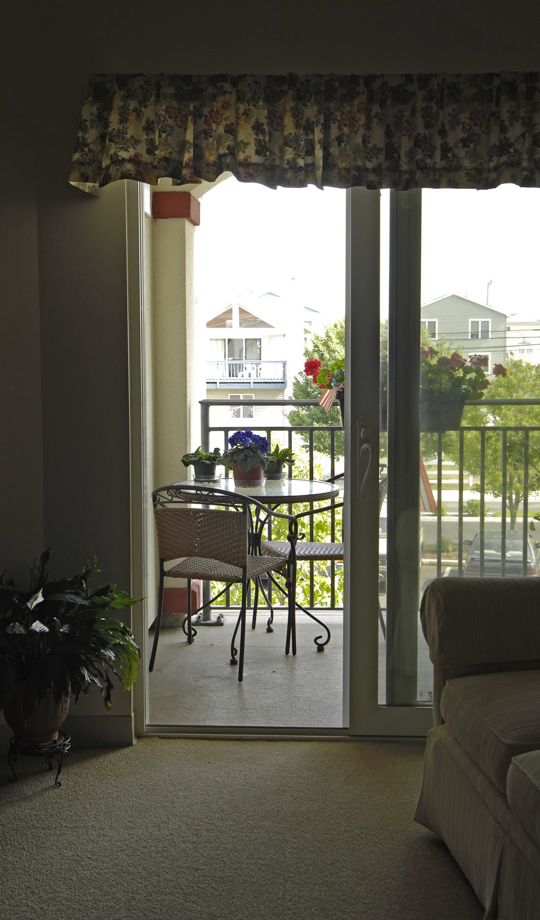 A cozy balcony with a small table and chairs, overlooking a residential neighborhood on a sunny day.