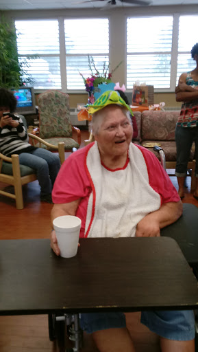An elderly woman joyfully celebrating a birthday, wearing a colorful party hat and enjoying the festivities.