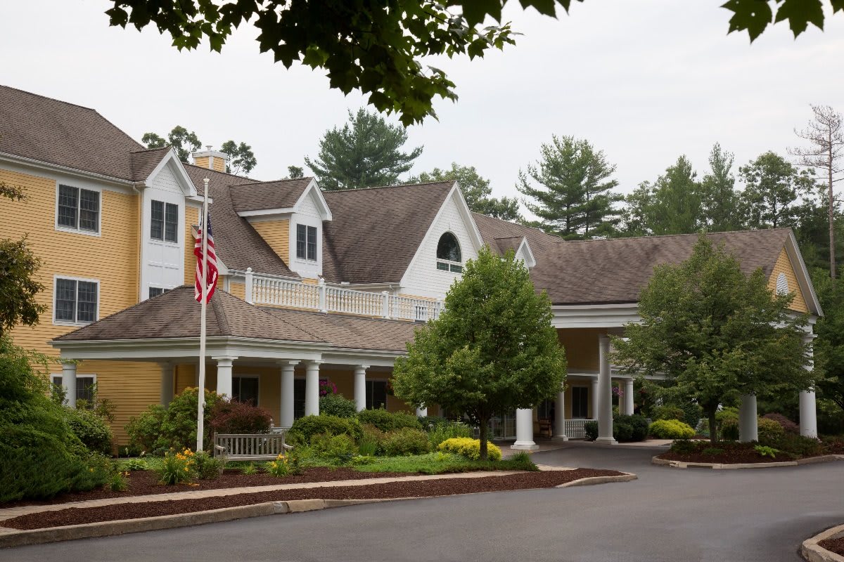 A picturesque residential building with an American flag and surrounding greenery.