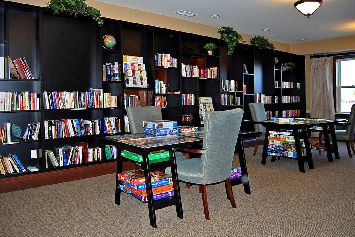 A cozy library with bookshelves, tables, and chairs for reading.
