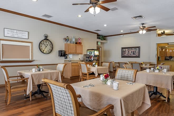 A cozy dining room with neatly set tables and warm lighting.