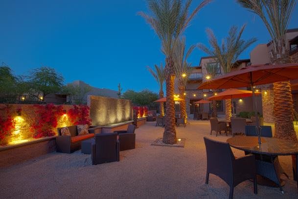 An inviting outdoor patio with palm trees and ambient evening lighting.