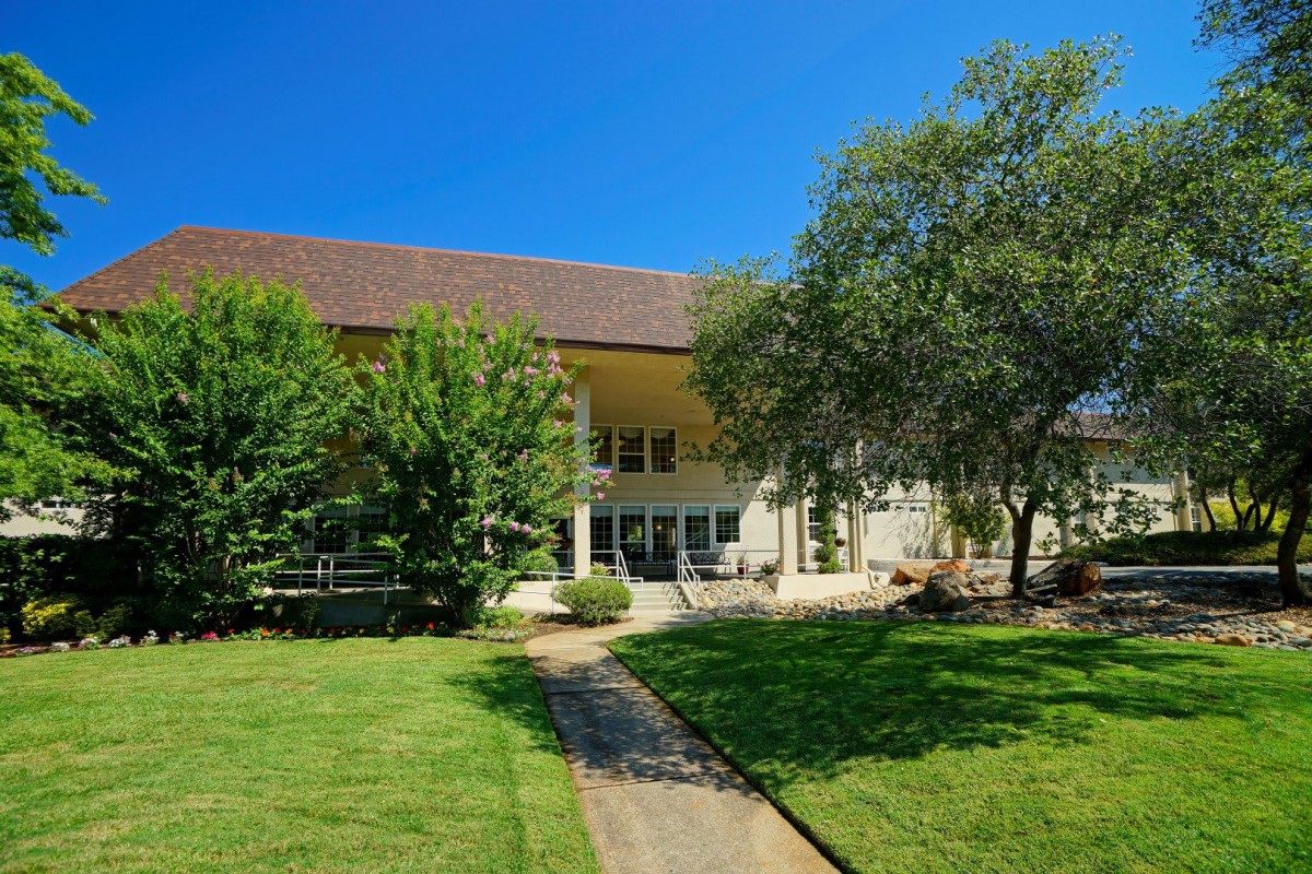 A spacious house with a large lawn and trees under a clear blue sky.