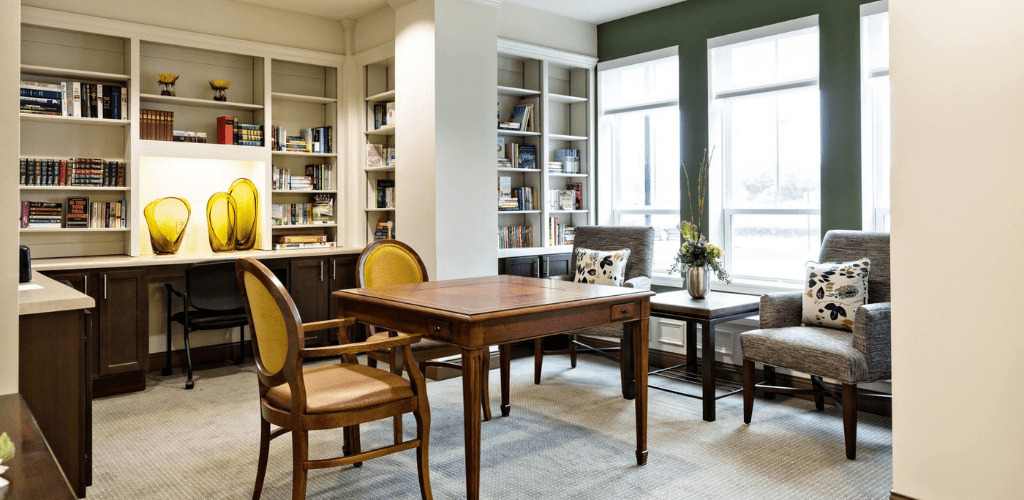 A cozy reading room with bookshelves and comfortable seating by the window.