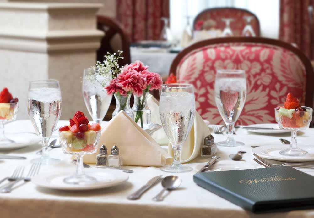 Elegant fine dining table setup with glasses, silverware, and flowers.