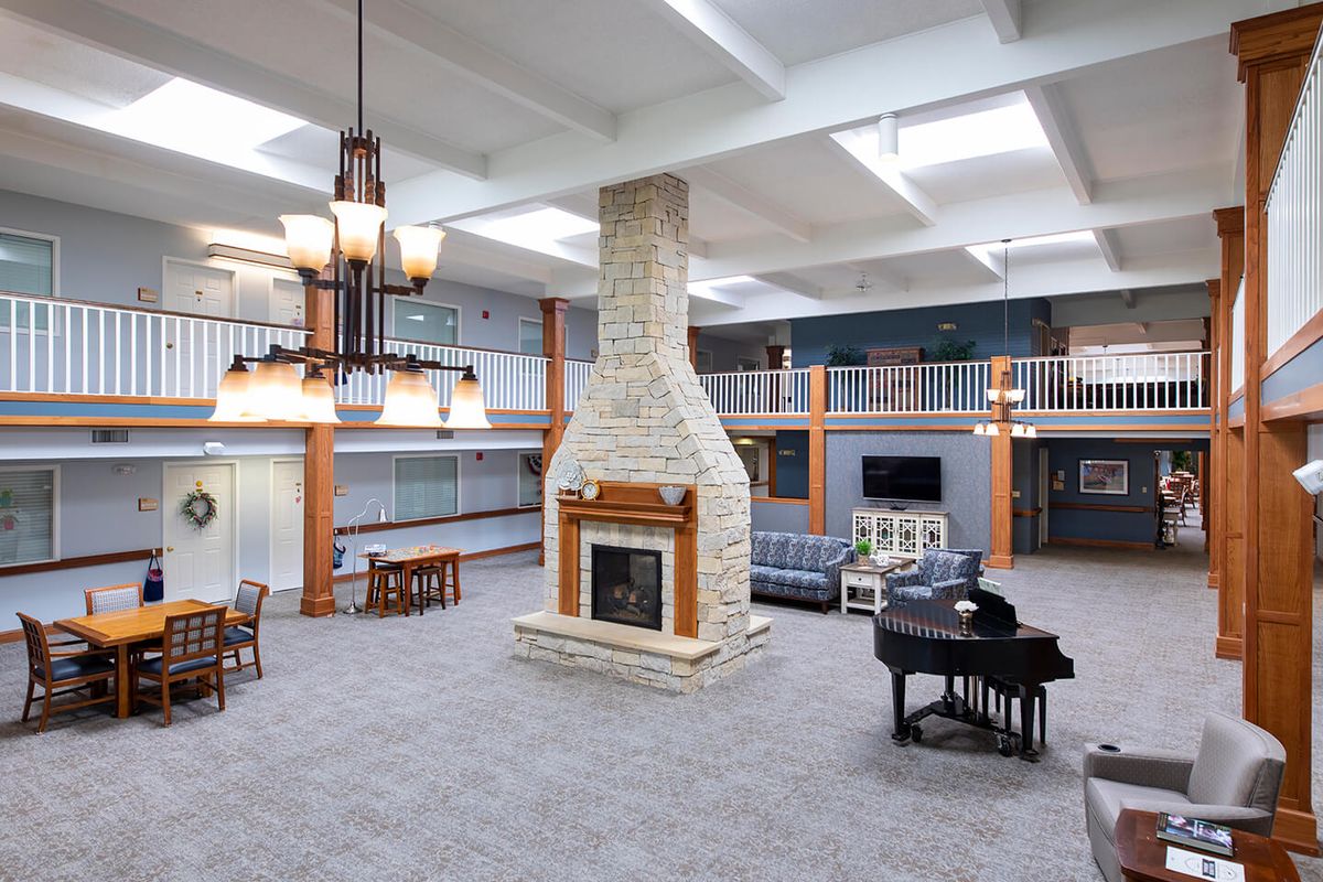 A spacious modern lobby with a central fireplace and grand piano, surrounded by seating areas.