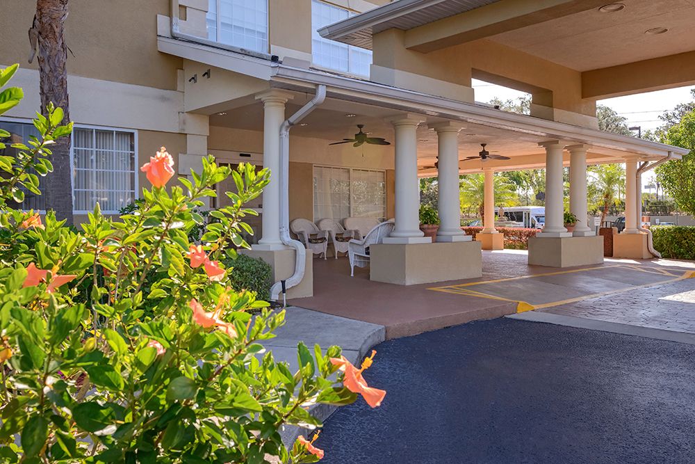 Hotel entrance with a covered patio and blooming flowers.