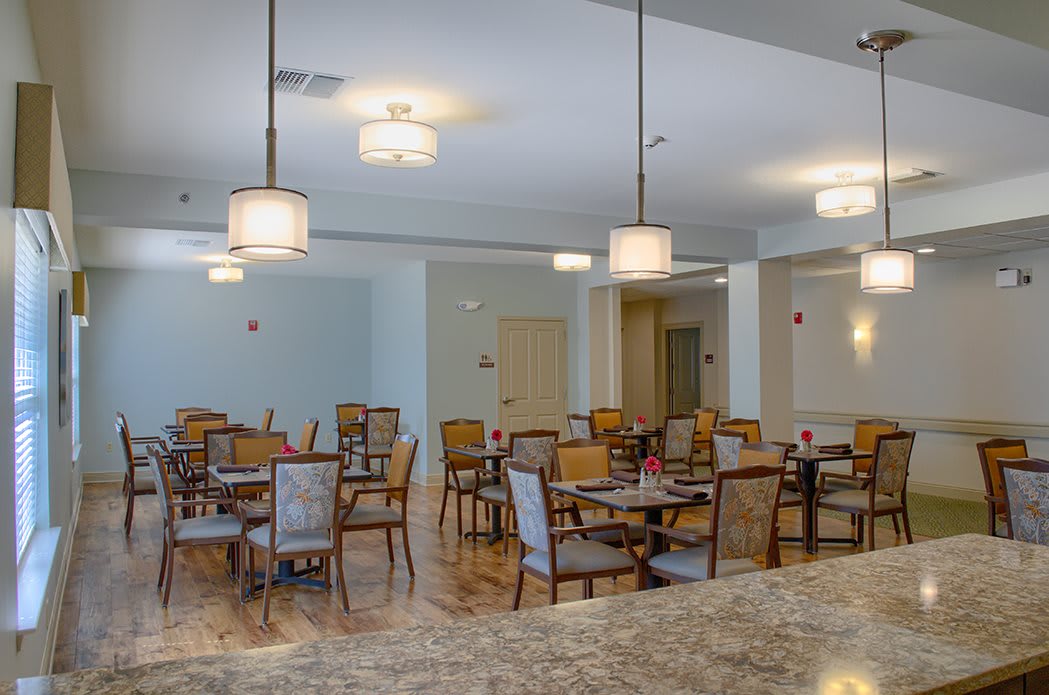 A spacious dining area with neatly arranged tables and chairs under modern lighting.