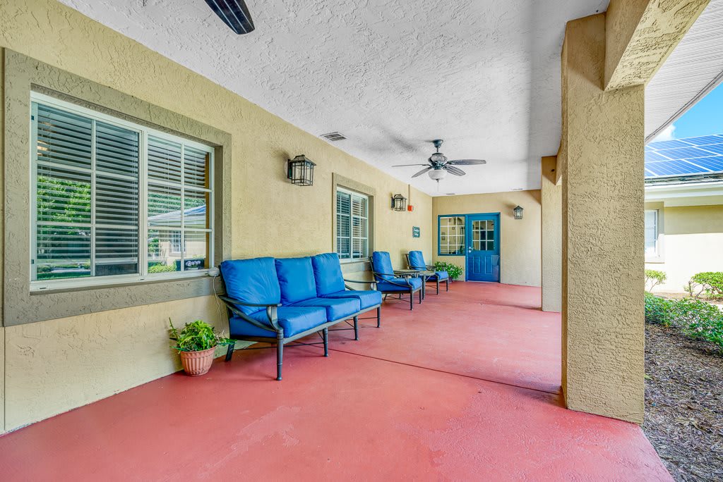 A spacious covered patio with blue cushioned seating and ceiling fans.