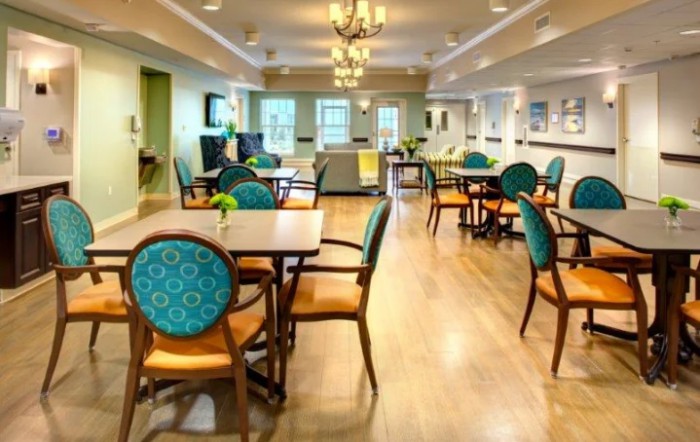 A brightly lit dining area with elegant chairs and tables, featuring a wooden floor and decorative lighting.