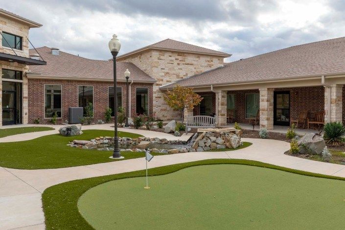 A residential building with a landscaped outdoor area featuring a putting green.