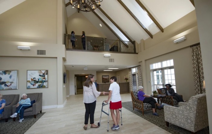 A spacious lobby with high ceilings, featuring people engaged in conversation and enjoying the well-lit area.