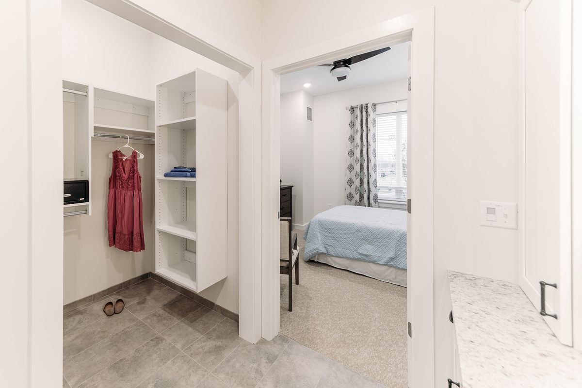 A minimalist bedroom with an adjacent closet, featuring simple furnishings and a clean design.