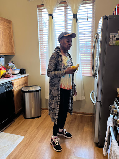 A woman standing in her kitchen, holding a yellow item while looking at the fridge.