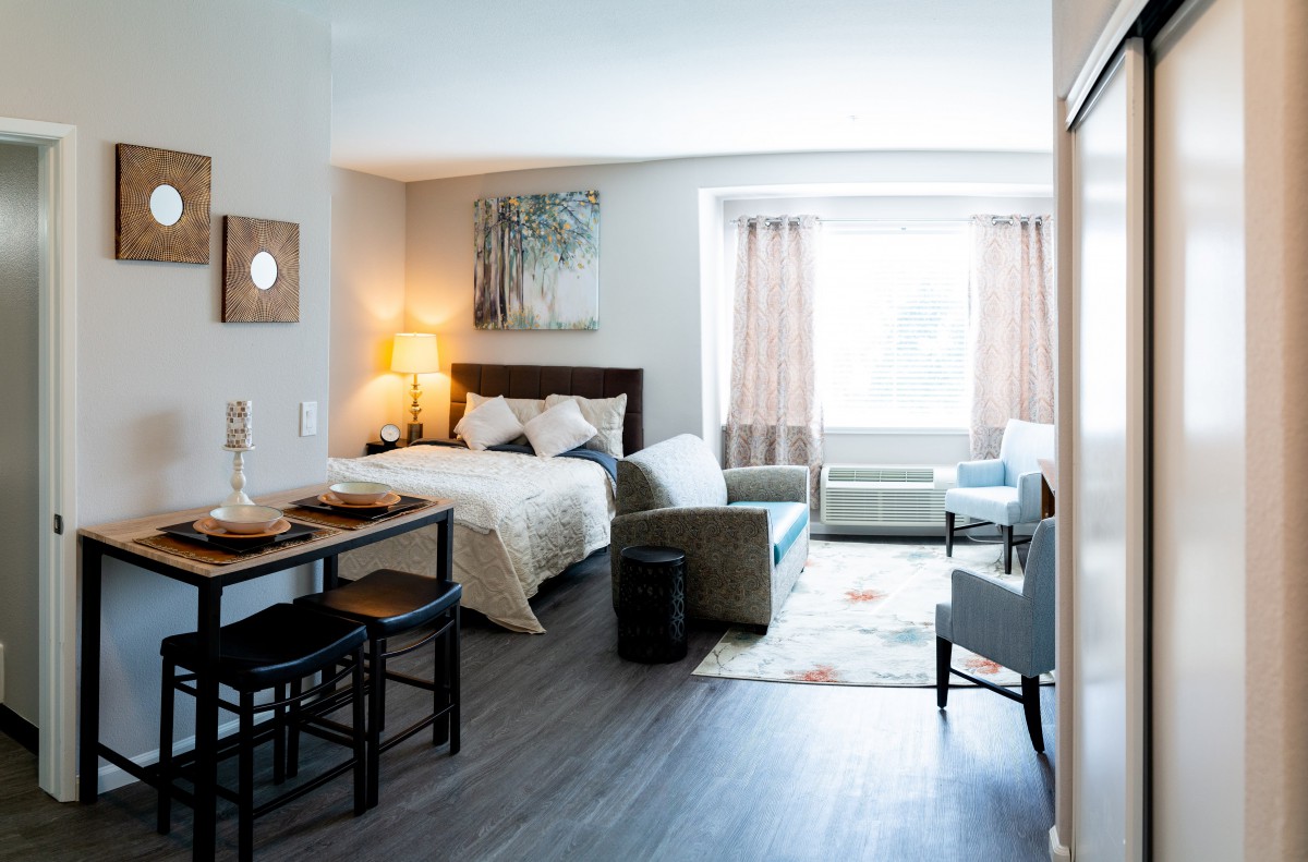 A modern studio apartment featuring a combined living and sleeping area with contemporary furniture.