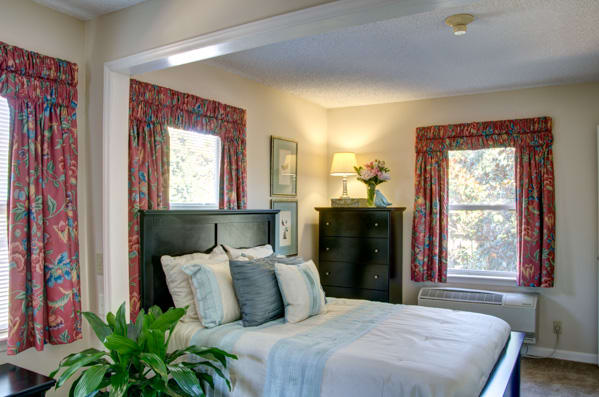 A cozy bedroom featuring a neatly made bed, stylish lamp, and decorative accents.