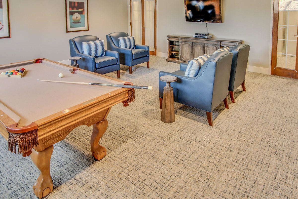 A cozy game room featuring a pool table, comfortable chairs, and a television.