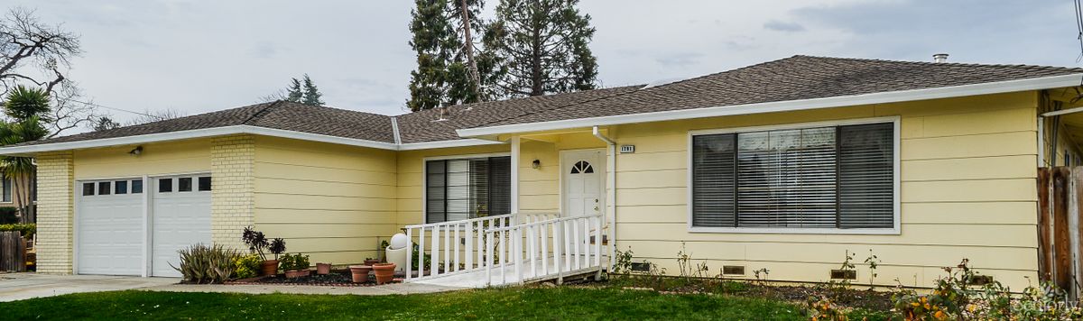 A single-story yellow house with a front entrance ramp and a green yard.