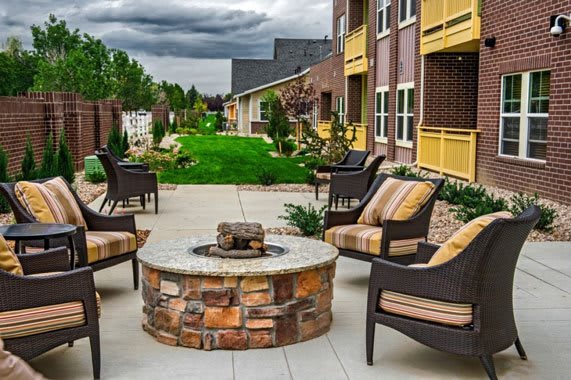Outdoor patio area with a fire pit and seating at an apartment complex.
