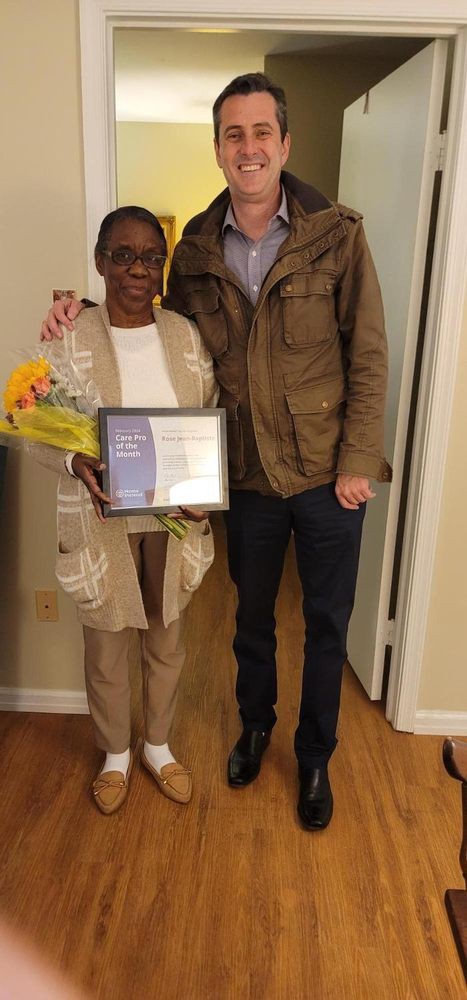 Two people posing with a certificate and bouquet of flowers.