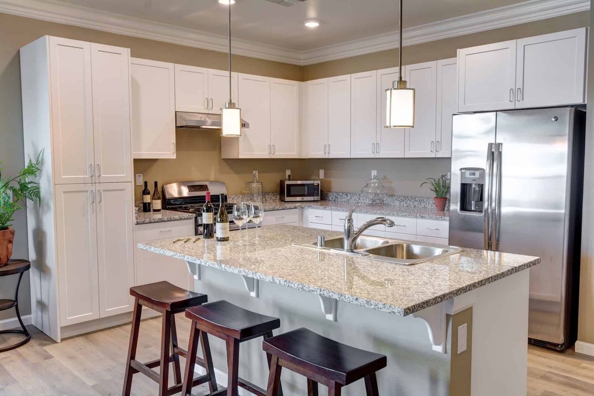 A modern kitchen with white cabinets, granite countertops, and pendant lighting.