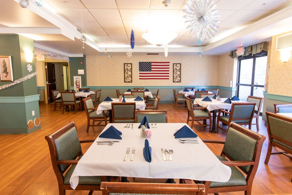 A dining area with neatly arranged tables and chairs, decorated with an American flag on the wall.