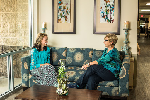 Two women engaging in a thoughtful conversation in a cozy indoor environment.