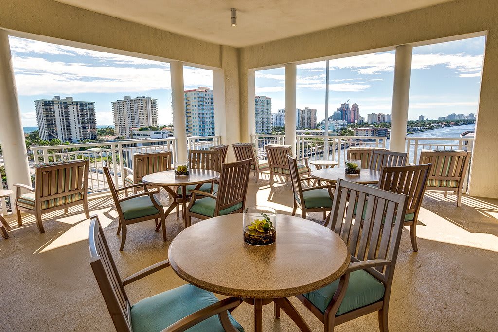 A cozy restaurant area with wooden tables and chairs, offering a stunning city view from the balcony.
