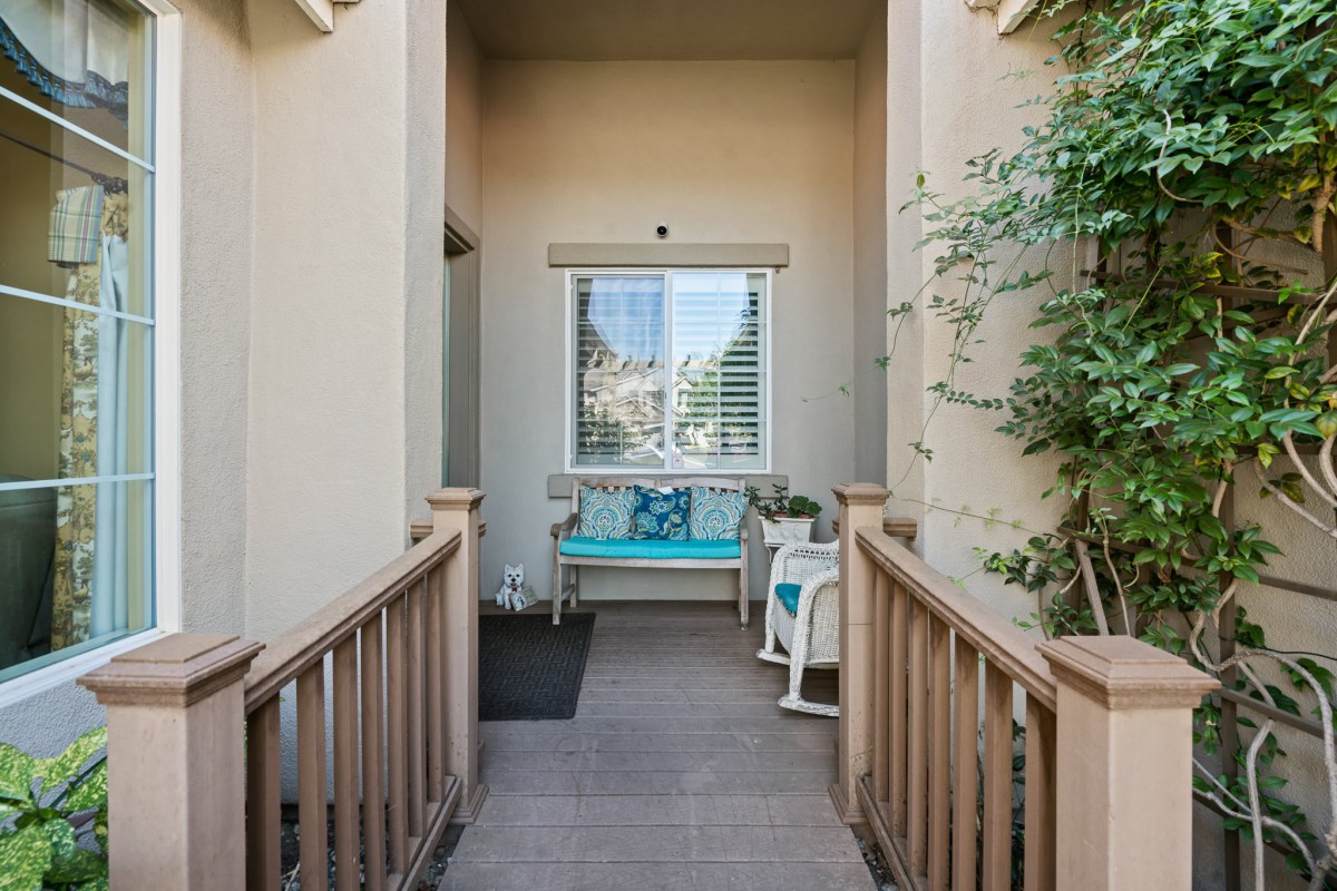 A cozy entryway with a bench and potted plants, leading to a windowed facade.
