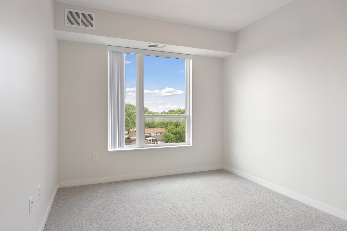 A minimalist empty room with a large window and white walls.
