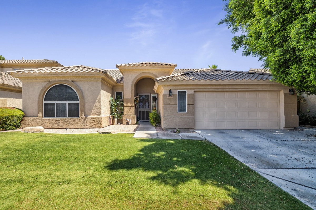 A suburban house with a well-maintained lawn and attached garage under a clear blue sky.